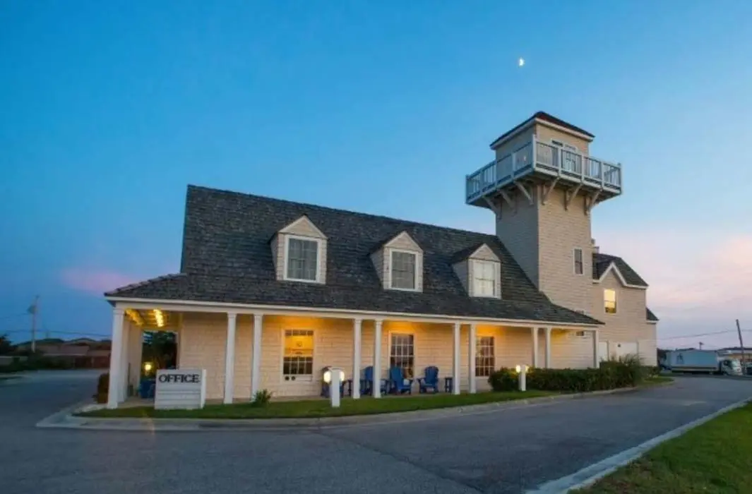 The inn's porch and shingled tower lit up at dusk, seen from the parking lot