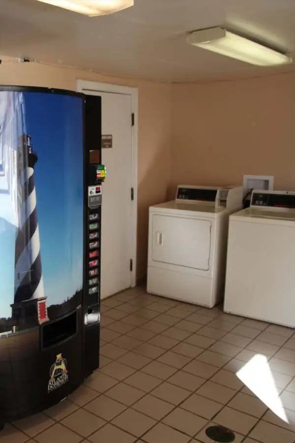 The guest laundry room, with a vending machine printed with the Cape Hatteras Lighthouse beside a washer and dryer