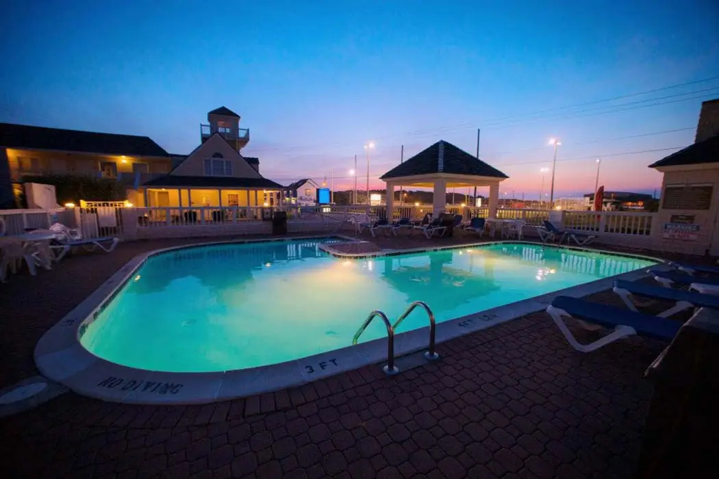 The outdoor pool at dusk, lit turquoise, with the covered pavilion and the inn’s tower and guest wing behind it